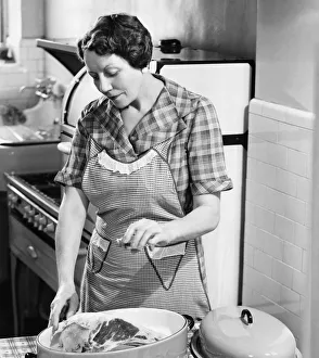 Woman seasoning meat in roasting dish (B&W) Woman seasoning meat in roasting dish (B&W)
