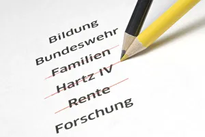 A yellow and a black pencil crossing out the letterings Familien, Hartz IV and Rente A yellow and a black pencil crossing out the letterings Familien, Hartz IV and Rente