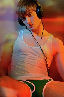 Young man in underwear with headphones in colorful light Young man in underwear with headphones in colorful light