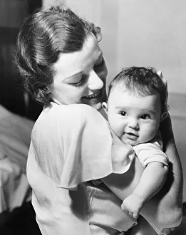 Young mother holding baby boy (9-12 months) in arms, (B&W) Young mother holding baby boy (9-12 months) in arms, (B&W)