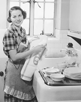 Young woman drying dishes in kitchen (B&W), portrait Young woman drying dishes in kitchen (B&W), portrait