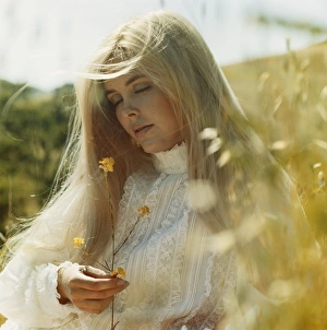 Young woman in field holding flower, eyes closed Young woman in field holding flower, eyes closed