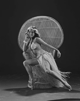 Young woman hula dancer in traditional clothing sitting on wicker chair, smiling, portrait Young woman hula dancer in traditional clothing sitting on wicker chair, smiling, portrait