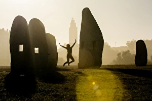 Young woman jumping in midair outdoors, in front of Hercules Tower, A Coruna, Spain Young woman jumping in midair outdoors, in front of Hercules Tower, A Coruna, Spain
