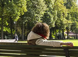 Young woman sitting on a bench watching a man speaking on the phone, Berlin, Germany Young woman sitting on a bench watching a man speaking on the phone, Berlin, Germany