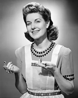Young woman wearing apron, standing, smiling, (B&W) Young woman wearing apron, standing, smiling, (B&W)