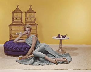 Young women lying and holding beer glass while birdcage in background Young women lying and holding beer glass while birdcage in background