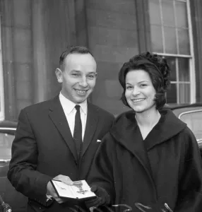 John Surtees with Miss Patricia Burke outside Buckingham Palace after he collected John Surtees with Miss Patricia Burke outside Buckingham Palace after he collected