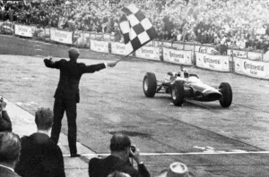 John Surtees roars across the finish line in his Ferrari to win the German Grand Prix at Adenau John Surtees roars across the finish line in his Ferrari to win the German Grand Prix at Adenau