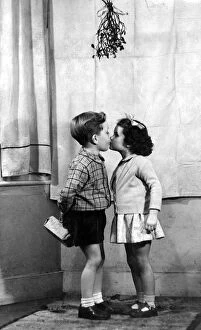 Images Dated 18th November 2004: Young boy and girl kissing underneath the mistletoe at Christmas time 1956 love