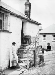 Teresa Mallett on cottage steps carrying a wooden barrel pail. Port Gaverne, St Endellion, Cornwall. 1906 Teresa Mallett on cottage steps carrying a wooden barrel pail. Port Gaverne, St Endellion, Cornwall. 1906