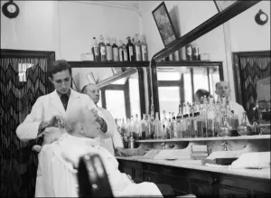 Prints of Un homme se fait coiffer dans un salon de coiffure a Paris dans les annees 1950. / AFP PHOTO man getting a haircut in a barber shop in Paris in the 1950s /AFP PHOTO Fashion Prints: 1950s Parisian Barber Shop Print