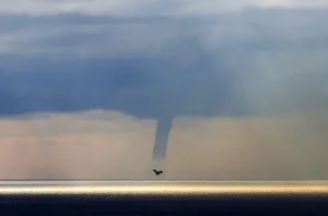 A waterspout forms on the horizon above the Mediterranean sea, off the coastal city A waterspout forms on the horizon above the Mediterranean sea, off the coastal city