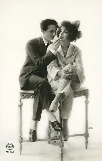 Androgynous man in suit applying lipstick to lips of girl in pyjamas (b/w photo) Androgynous man in suit applying lipstick to lips of girl in pyjamas (b/w photo)