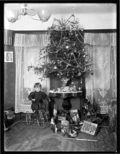 Seymour boy posed seated on tricycle beside Christmas tree in parlor Seymour boy posed seated on tricycle beside Christmas tree in parlor