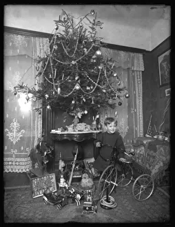 Seymour boy posed with tricycle beside Christmas tree in parlor Seymour boy posed with tricycle beside Christmas tree in parlor
