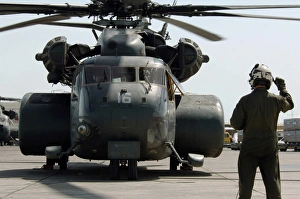 Air crewman gives the engine start up signal to pilots aboard a MH-53E Sea Dragon Air crewman gives the engine start up signal to pilots aboard a MH-53E Sea Dragon