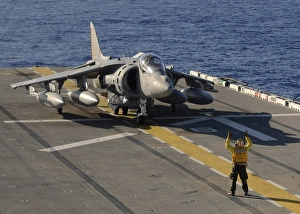 An Airman directs an AV-8B Harrier jet aircraft on the flight deck of USS Essex An Airman directs an AV-8B Harrier jet aircraft on the flight deck of USS Essex