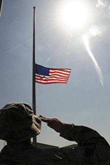 An Airman salutes the American flag that is flying at half-mast An Airman salutes the American flag that is flying at half-mast