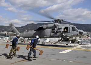 Airmen prepare to chock and chain an MH-60S Sea Hawk helicopter Airmen prepare to chock and chain an MH-60S Sea Hawk helicopter