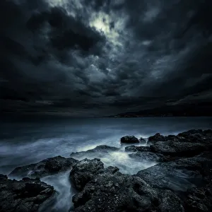 Black rocks protruding through rough seas with stormy clouds, Crete, Greece Black rocks protruding through rough seas with stormy clouds, Crete, Greece
