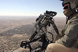 A crew chief looks for suspicious activity while manning a machine gun aboard a helicopter A crew chief looks for suspicious activity while manning a machine gun aboard a helicopter