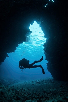 Diver In Pacific Ocean Prints: A diver exiting a swim through cavern