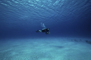A diver on a scooter explores the clear blue waters of Toris Reef, Bonaire A diver on a scooter explores the clear blue waters of Toris Reef, Bonaire