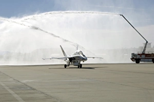 An F-18 aircraft taxies beneath the spray from fire trucks An F-18 aircraft taxies beneath the spray from fire trucks