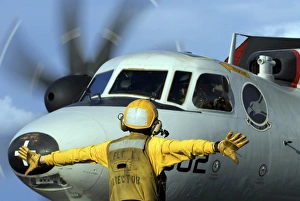 A flight deck director signals the pilot of an E-2C Hawkeye to spread his wings A flight deck director signals the pilot of an E-2C Hawkeye to spread his wings