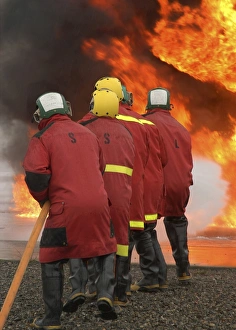 A flight deck fire party battles a controlled fire A flight deck fire party battles a controlled fire