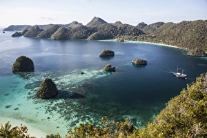 Forest-covered limestone islands surround a lagoon in Raja Ampat Forest-covered limestone islands surround a lagoon in Raja Ampat
