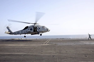 A helicopter landing signalman directs an SH-60F Sea Hawk A helicopter landing signalman directs an SH-60F Sea Hawk