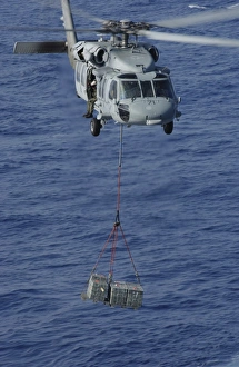 An MH-60S Knighthawk transports supplies during a replenishment at sea An MH-60S Knighthawk transports supplies during a replenishment at sea