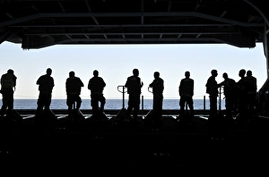 Silhouette of sailors standing in the hangar bay aboard USS Carl Vinson Silhouette of sailors standing in the hangar bay aboard USS Carl Vinson