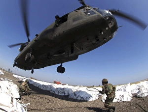 Specialists attach cargo hooks supporting large bags of sand to a CH-47 Chinook helicopter Specialists attach cargo hooks supporting large bags of sand to a CH-47 Chinook helicopter