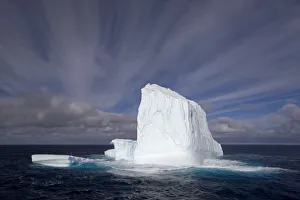 Huge iceberg with streaked sky under expansive open sky Huge iceberg with streaked sky under expansive open sky