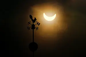 Natural Science Photography Prints: Partial solar eclipse above silhouette of weather vane, Wroclaw, Poland. 3rd March, 2015