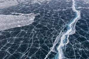 Transparent black ice with cracks on Lake Baikal, aerial shot Transparent black ice with cracks on Lake Baikal, aerial shot