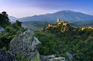 The village of Eus perched on a hilltop with sunlight with the Pic de Canigou beyond The village of Eus perched on a hilltop with sunlight with the Pic de Canigou beyond