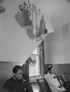 Sitting beneath the emblem of the crucifixion of Jesus on Calvary, Washington, D.C. 1942. Creator: Gordon Parks Sitting beneath the emblem of the crucifixion of Jesus on Calvary, Washington, D.C. 1942. Creator: Gordon Parks