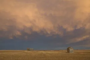 Alberta, Canada; A Wooden Shack On A Cut Wheat Field With A Dramatic Cloudy Sky At Sunset Alberta, Canada; A Wooden Shack On A Cut Wheat Field With A Dramatic Cloudy Sky At Sunset