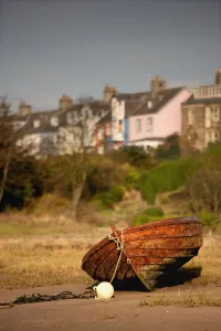 Alnmouth, Northumberland, England; An Abandoned, Rusted Boat Sitting On Land With Houses In The Background Alnmouth, Northumberland, England; An Abandoned, Rusted Boat Sitting On Land With Houses In The Background
