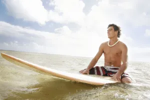 Hawaii, Oahu, Young Man Sitting On His Surfboard At The Shoreline Hawaii, Oahu, Young Man Sitting On His Surfboard At The Shoreline