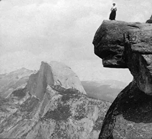 Historic image in black and white of a woman standing on a high cliff at Yosemite National Park; California Historic image in black and white of a woman standing on a high cliff at Yosemite National Park; California