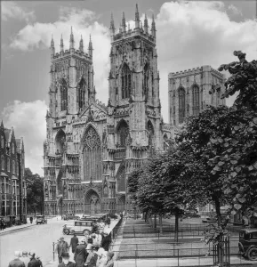 Historic image in black and white of York Minster Cathedral with pedestrians and cars on the street, circa 1920; York Historic image in black and white of York Minster Cathedral with pedestrians and cars on the street, circa 1920; York