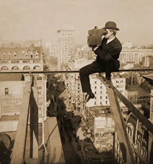 Historic image in sepia of a photographer sitting on a slender girder above fifth avenue in New York City with a Historic image in sepia of a photographer sitting on a slender girder above fifth avenue in New York City with a
