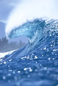 Large Shimmery Blue Wave Curling With Wind Spray, Land Visible In Background Large Shimmery Blue Wave Curling With Wind Spray, Land Visible In Background