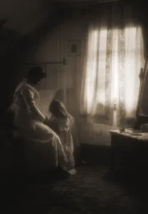 A mother and child saying bedtime prayers with child kneeling at the bed beside a window A mother and child saying bedtime prayers with child kneeling at the bed beside a window