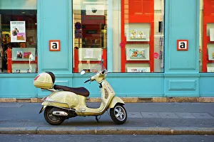 A Motorized Scooter Parked Outside A Blue Building Along A Street, Canal Saint Martin; Paris, France A Motorized Scooter Parked Outside A Blue Building Along A Street, Canal Saint Martin; Paris, France